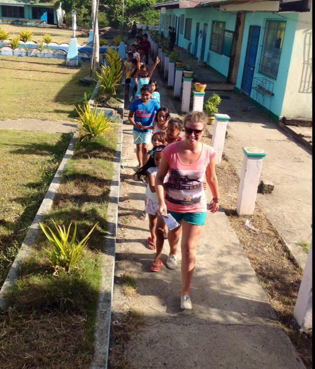 Female Childcare volunteer leads a group of kindergarten children around a garden at her Childcare placement in Philippines. Projects Abroad volunteer working with children in Philippines leads school children outside their kindergarten at her Childcare Project.